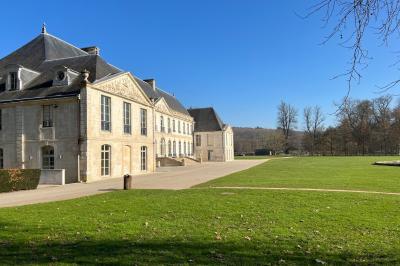 Un grand groupe de personnes posant devant un bâtiment historique en pierre avec des fenêtres et des balcons.