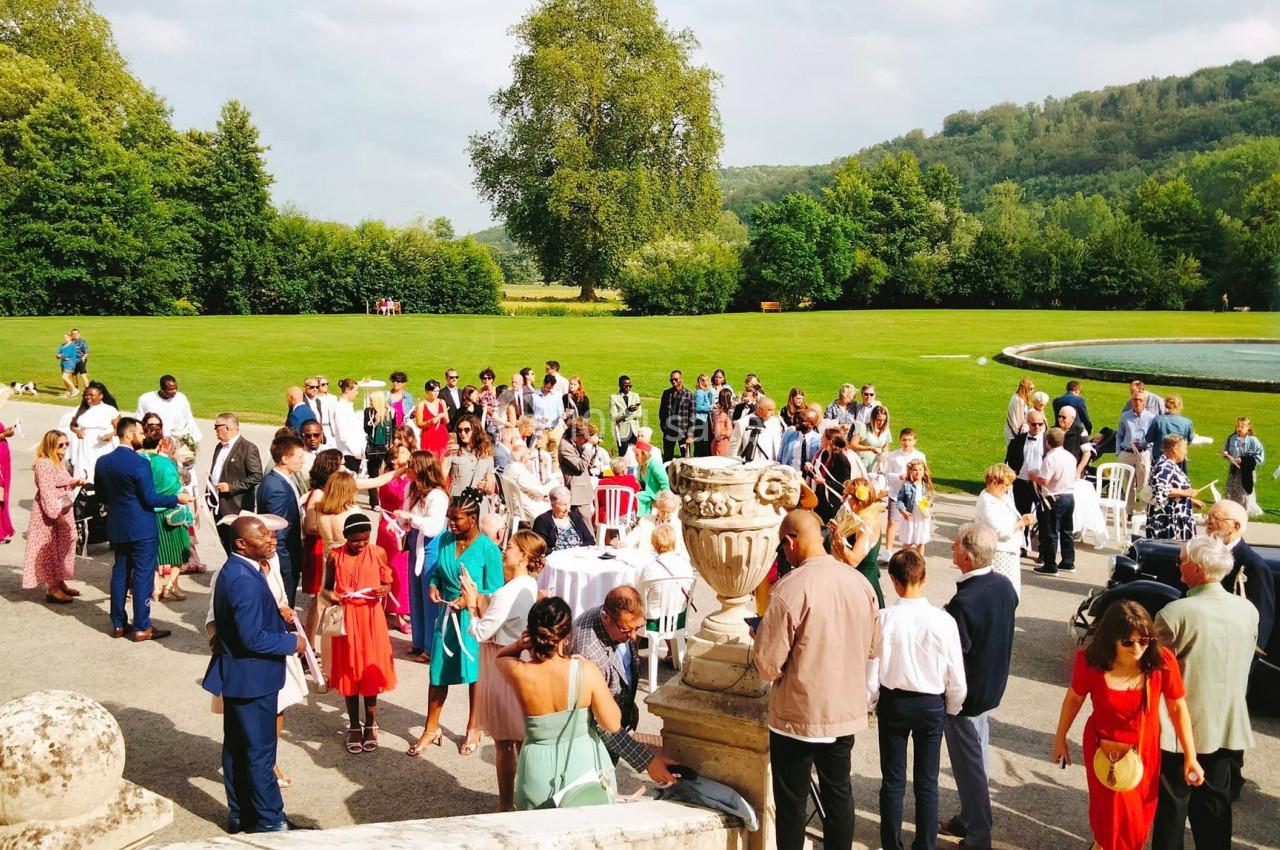 Groupe de personnes rassemblées en extérieur dans un parc, près d'une fontaine et de verdure, lors d'un événement.