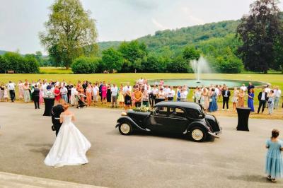 Un grand groupe de personnes posant devant un bâtiment historique en pierre avec des fenêtres et des balcons.
