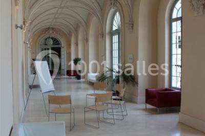 Salle voûtée élégamment dressée pour un repas, avec tables ornées de nappes blanches, verres et assiettes décorées.