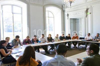 Salle voûtée élégamment dressée pour un repas, avec tables ornées de nappes blanches, verres et assiettes décorées.