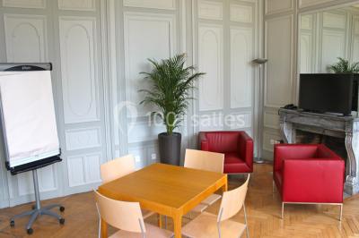 Salle voûtée élégamment dressée pour un repas, avec tables ornées de nappes blanches, verres et assiettes décorées.