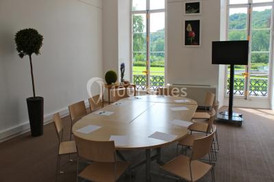 Salle voûtée élégamment dressée pour un repas, avec tables ornées de nappes blanches, verres et assiettes décorées.