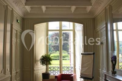 Salle voûtée élégamment dressée pour un repas, avec tables ornées de nappes blanches, verres et assiettes décorées.
