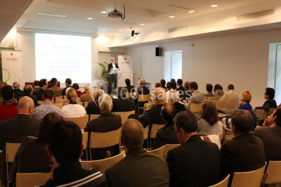 Salle voûtée élégamment dressée pour un repas, avec tables ornées de nappes blanches, verres et assiettes décorées.