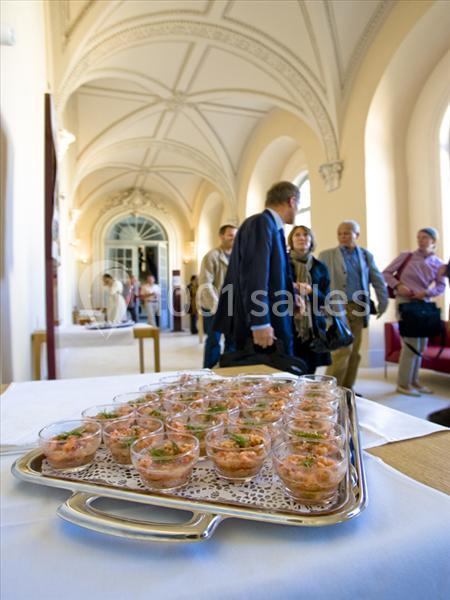 Plateau de verrines disposé sur une table dans une salle lumineuse avec des invités en arrière-plan.