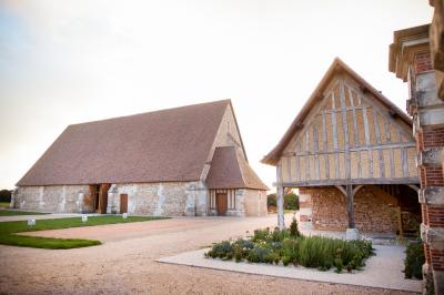 Chemin de gravier bordé d'herbe et d'arbres, avec des voitures garées en arrière-plan sous un ciel nuageux.