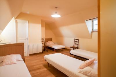 Chemin de gravier bordé d'herbe et d'arbres, avec des voitures garées en arrière-plan sous un ciel nuageux.