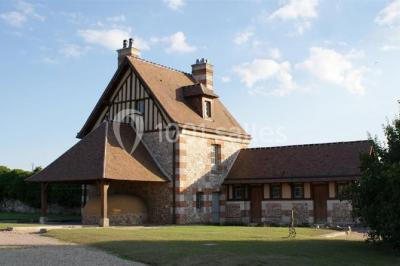 Chemin de gravier bordé d'herbe et d'arbres, avec des voitures garées en arrière-plan sous un ciel nuageux.