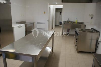 Chemin de gravier bordé d'herbe et d'arbres, avec des voitures garées en arrière-plan sous un ciel nuageux.