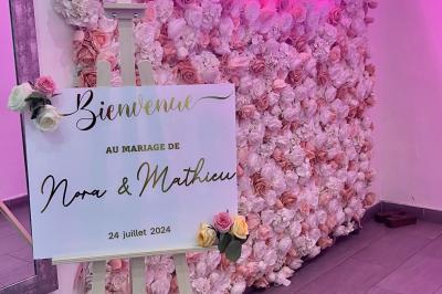 Salle de réception élégante avec tables décorées de fleurs blanches, chaises transparentes et éclairage tamisé.