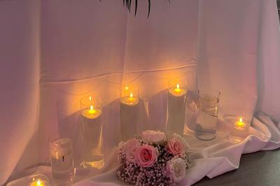 Salle de réception élégante avec tables décorées de fleurs blanches, chaises transparentes et éclairage tamisé.