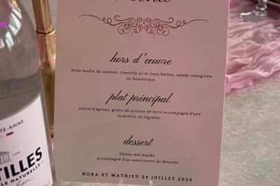 Salle de réception élégante avec tables décorées de fleurs blanches, chaises transparentes et éclairage tamisé.