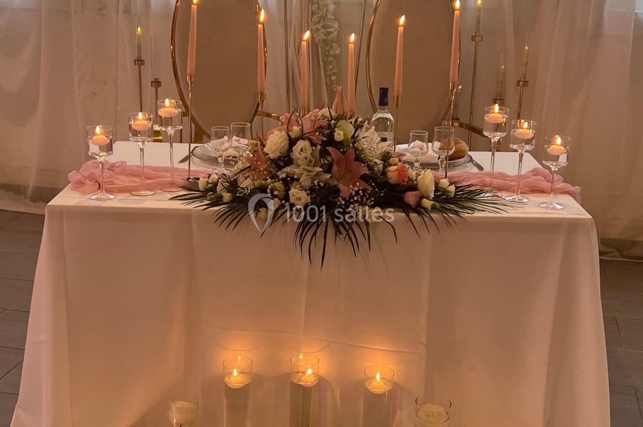 Table décorée pour un mariage avec bougies, fleurs roses et blanches, et deux miroirs ovales en arrière-plan.