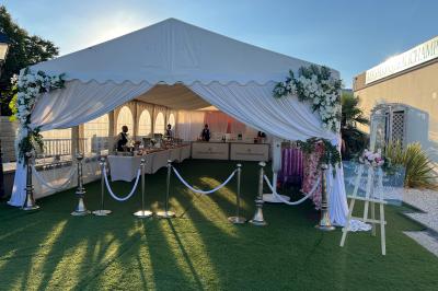 Salle de réception élégante avec tables décorées de fleurs blanches, chaises transparentes et éclairage tamisé.