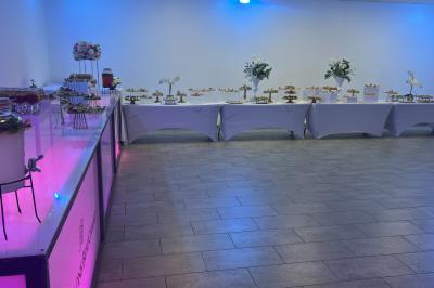 Salle de réception élégante avec tables décorées de fleurs blanches, chaises transparentes et éclairage tamisé.