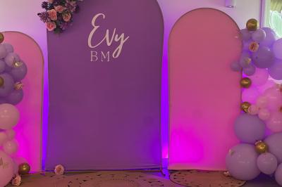 Salle de réception élégante avec tables décorées de fleurs blanches, chaises transparentes et éclairage tamisé.