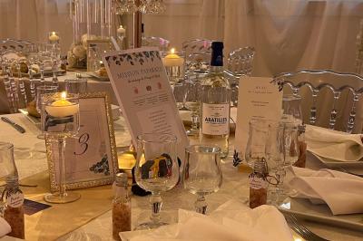 Salle de réception élégante avec tables décorées de fleurs blanches, chaises transparentes et éclairage tamisé.