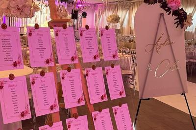Salle de réception élégante avec tables décorées de fleurs blanches, chaises transparentes et éclairage tamisé.