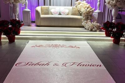 Salle de réception élégante avec tables décorées de fleurs blanches, chaises transparentes et éclairage tamisé.