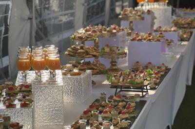 Salle de réception élégante avec tables décorées de fleurs blanches, chaises transparentes et éclairage tamisé.