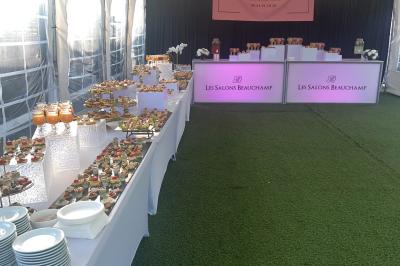 Salle de réception élégante avec tables décorées de fleurs blanches, chaises transparentes et éclairage tamisé.