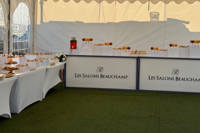 Salle de réception décorée pour un mariage, avec des tables élégantes, des fleurs blanches et une arche florale au premier…
