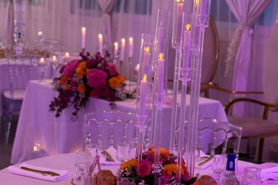 Salle de réception décorée pour un mariage, avec des tables élégantes, des fleurs blanches et une arche florale au premier…