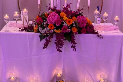 Salle de réception décorée pour un mariage, avec des tables élégantes, des fleurs blanches et une arche florale au premier…
