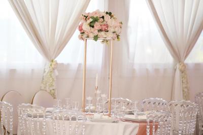 Salle de réception élégante avec tables décorées de fleurs blanches, chaises transparentes et éclairage tamisé.