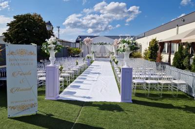 Salle de réception élégante avec tables décorées de fleurs blanches, chaises transparentes et éclairage tamisé.