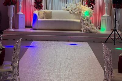 Salle de réception élégante avec tables décorées de fleurs blanches, chaises transparentes et éclairage tamisé.