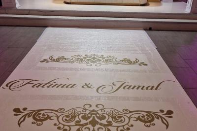 Salle de réception élégante avec tables décorées de fleurs blanches, chaises transparentes et éclairage tamisé.