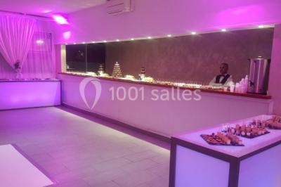 Salle de réception élégante avec tables décorées de fleurs blanches, chaises transparentes et éclairage tamisé.