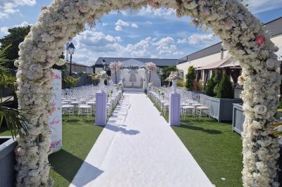 Salle de réception élégante avec tables décorées de fleurs blanches, chaises transparentes et éclairage tamisé.