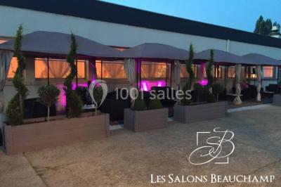 Salle de réception élégante avec tables décorées de fleurs blanches, chaises transparentes et éclairage tamisé.