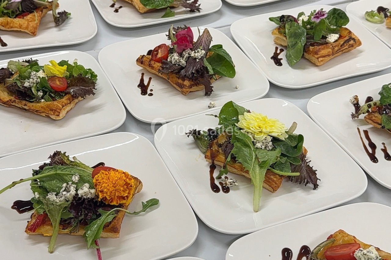 Assiettes de tartes salées garnies de légumes, herbes fraîches et fleurs comestibles, disposées sur une table.