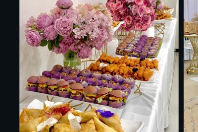 Salle lumineuse avec buffet décoré de fleurs, contenant des plats et boissons, sur un sol en carrelage blanc.