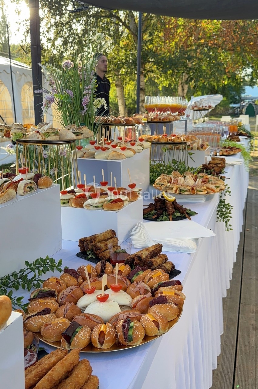 Buffet en plein air avec une variété de plats et amuse-bouches disposés sur des tables décorées de fleurs.