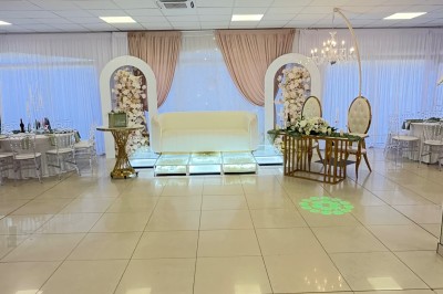 Salle de réception élégante avec tables dressées, chaises transparentes et décoration florale raffinée.