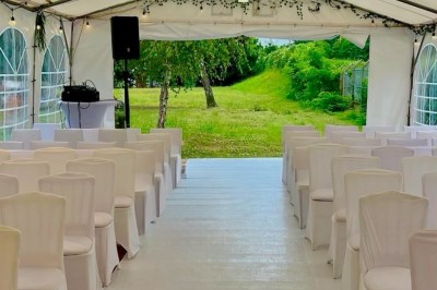 Salle de réception élégante avec tables dressées, chaises transparentes et décoration florale raffinée.