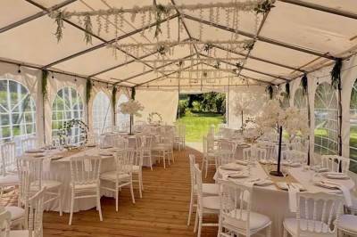 Salle de réception élégante avec tables dressées, chaises transparentes et décoration florale raffinée.