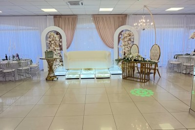 Salle de réception élégante avec tables dressées, chaises transparentes et décoration florale raffinée.