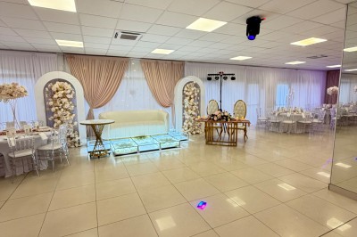Salle de réception élégante avec tables dressées, chaises transparentes et décoration florale raffinée.