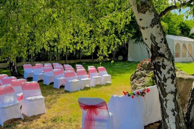 Salle de réception élégante avec tables dressées, chaises transparentes et décoration florale raffinée.