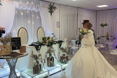 Salle de réception élégante avec tables dressées, chaises transparentes et décoration florale raffinée.