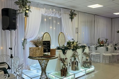 Salle de réception élégante avec tables dressées, chaises transparentes et décoration florale raffinée.