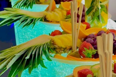 Allée décorée de fleurs blanches et éclairages colorés menant à un espace couvert en extérieur, de nuit.