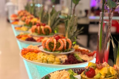 Allée décorée de fleurs blanches et éclairages colorés menant à un espace couvert en extérieur, de nuit.