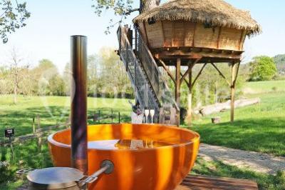 Chambre avec lit rond, couverture rouge, pétales de rose, lampe de chevet et plafond en bois avec suspension plumeuse.